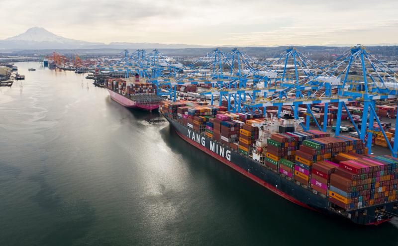 Ein großes Containerschiff der Marke Yang Ming liegt im Hafen an Ladestationen.