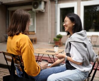 Zwei Frauen unterhalten sich bei Kaffee an einem Café-Tisch im Freien